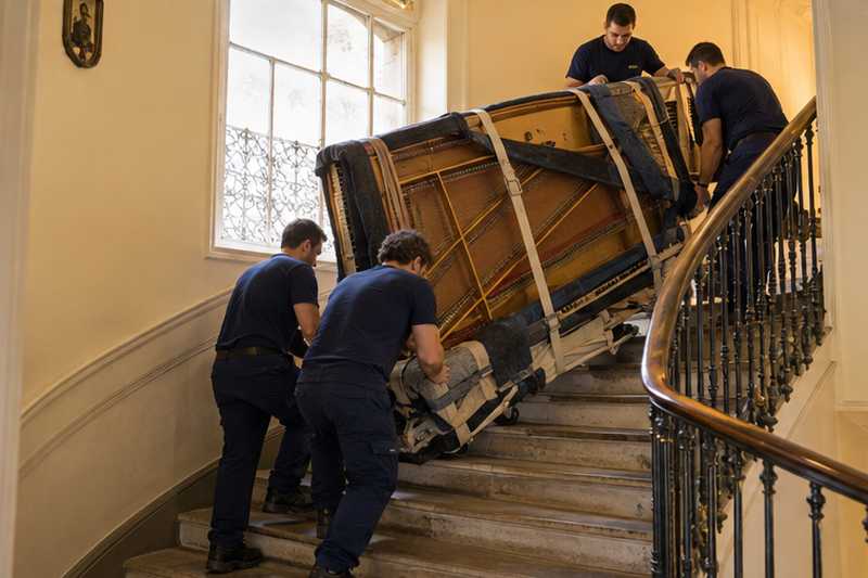 Piano quart de queue en cerisier allongé sur sa luge dans l'escalier